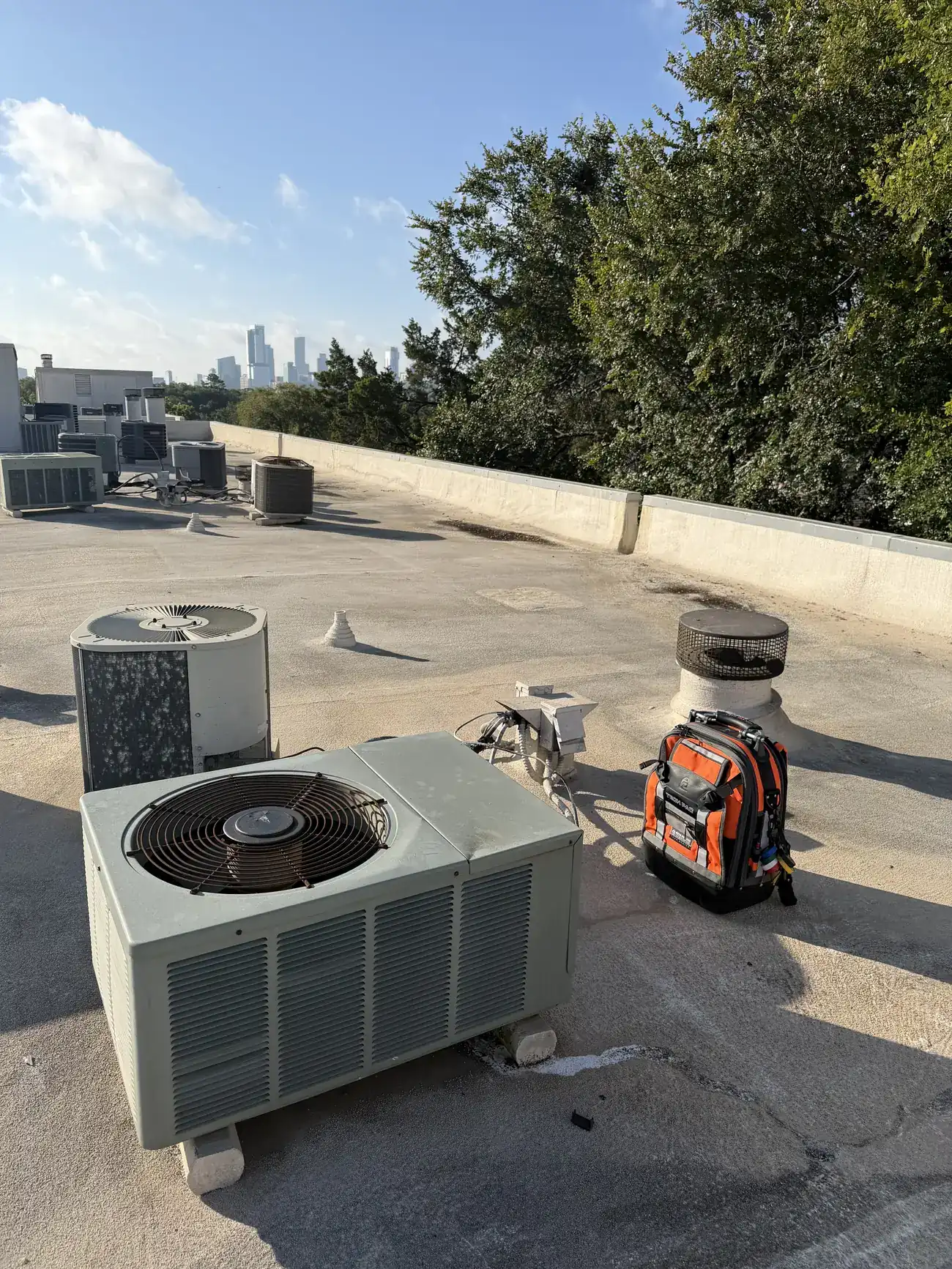 AC condenser on an Austin rooftop with the downtown skyline behind it