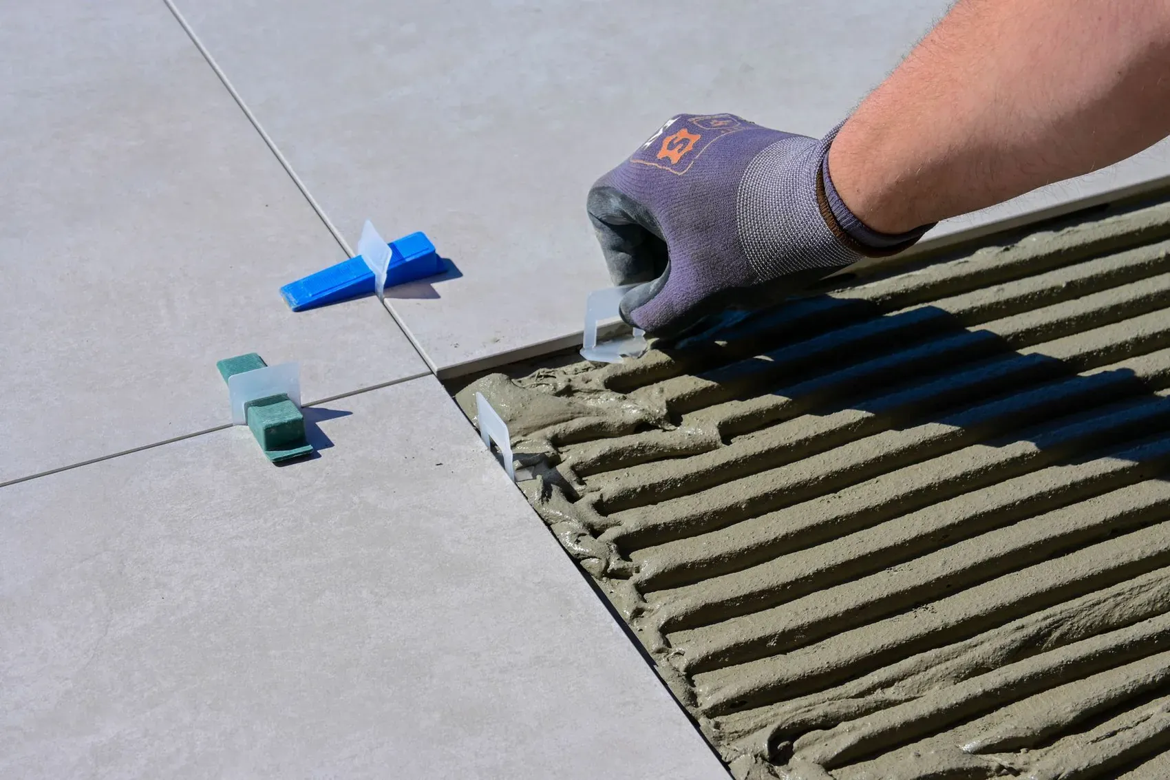 Gloved hands setting large-format tile into fresh thinset