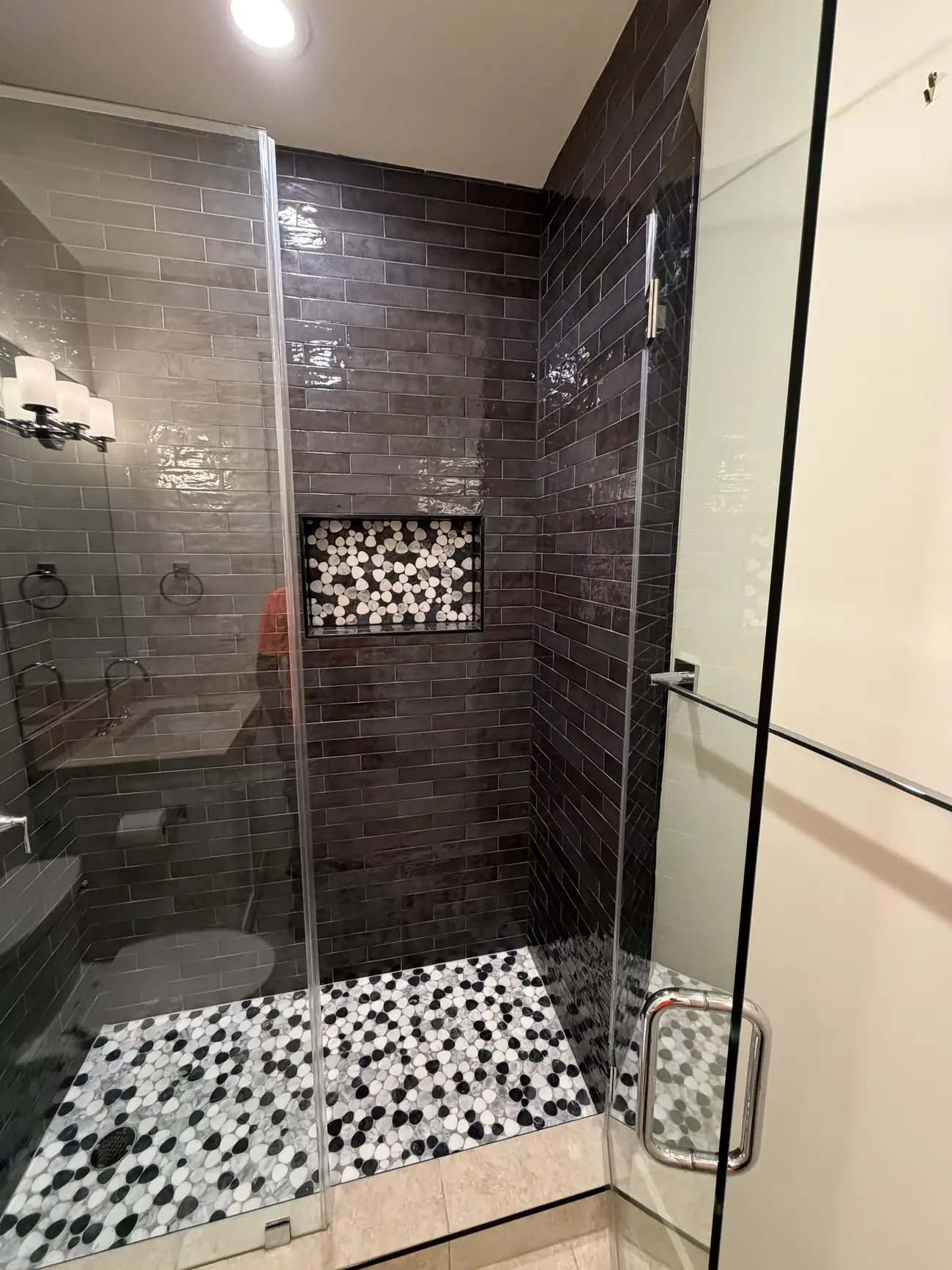 Finished walk-in glass shower with dark tile and a pebble floor in an Austin bathroom